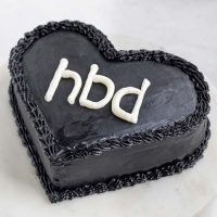 Image of a black heart cake with white initials on top.