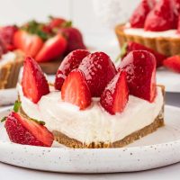 Close-up photo of a piece of cheesecake tart with halved strawberries on top