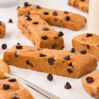 Photo of several peanut butter protein bars scattered on a white background along with chocolate chips