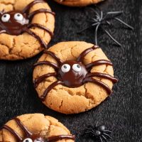 Photo showing easy to make Halloween spider cookies on a stark black background with black spider decorations set to the side.