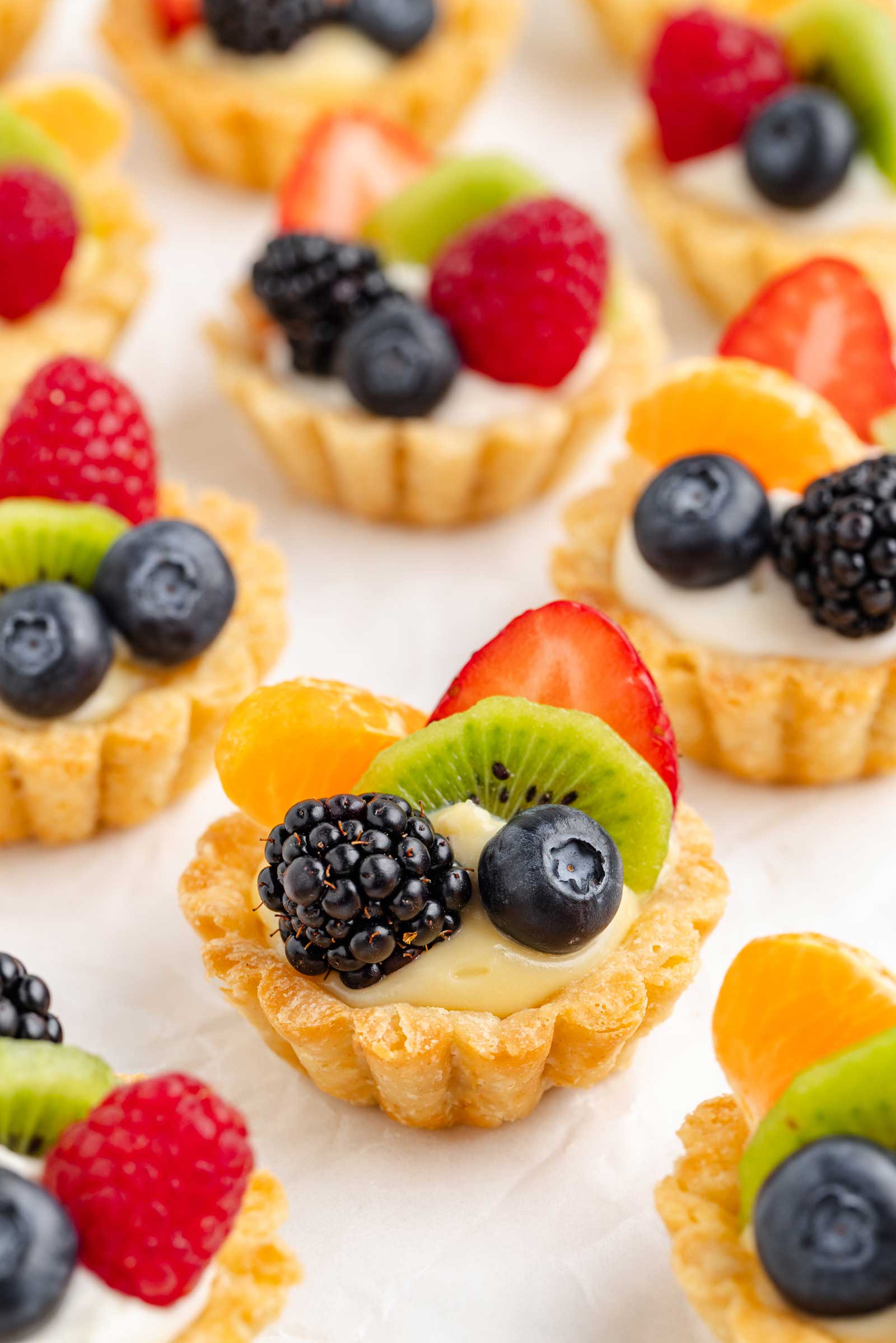 fruit tartlets spread out on white parchment paper