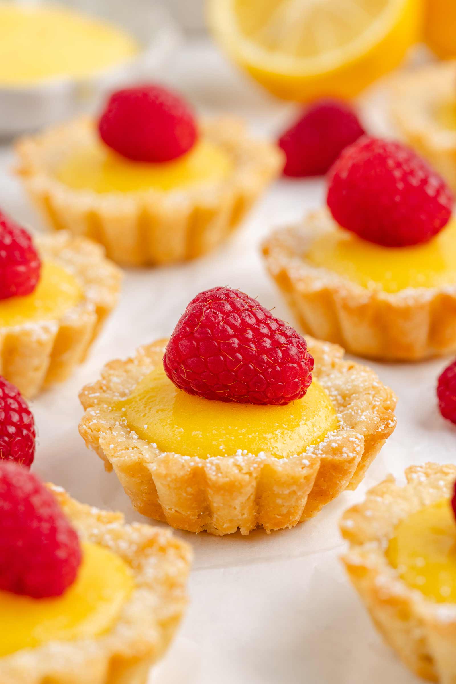 mini lemon tarts on white piece of parchment paper