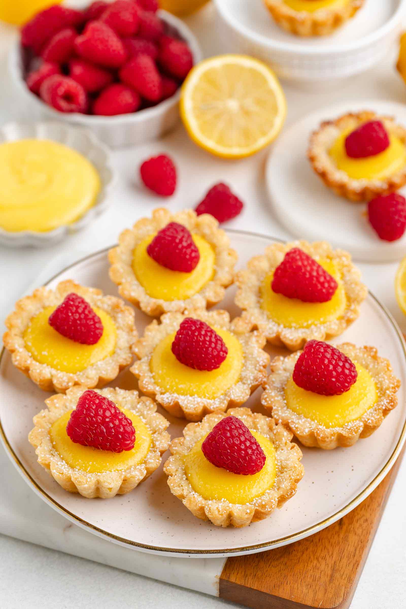 plate filled with lemon tartlets with raspberries on top